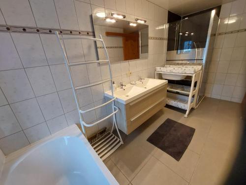een badkamer met een bad, een wastafel en een spiegel bij Les Gîtes du Rancourt - Sous la Grange & Le Logis in Sainte-Ode