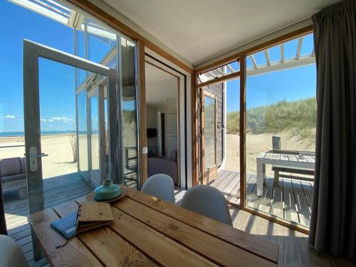 a dining room with a table and a view of the beach at Strandhuis, Beachhouse - Slapen op het strand, Sleep at the beach in Nieuwvliet