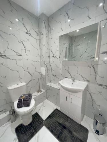 Baño blanco con aseo y lavamanos en Flitwick Luxury Apartment, en Flitwick