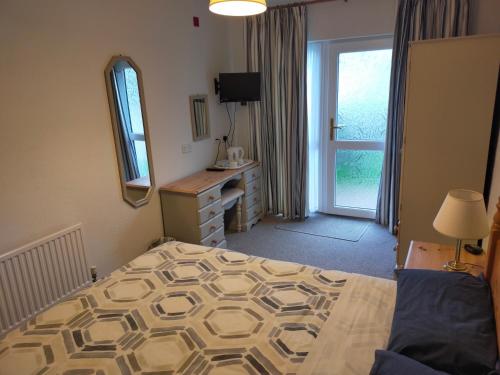 a bedroom with a bed and a mirror and a window at The Green Dragon Inn in Redditch