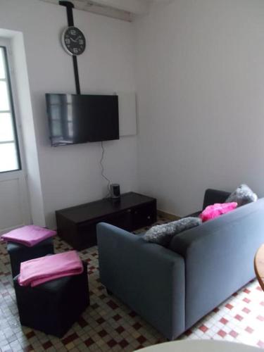 a living room with a couch and a tv at Gîte du Rempart in Saint-Justin