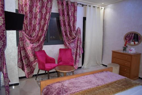 a bedroom with pink curtains and a bed and two chairs at Moonrise Villa VIP Midelt in Midelt