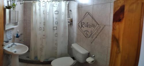 a bathroom with a white shower curtain and a toilet at Rikra Purmamarca in Purmamarca