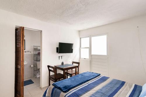 a bedroom with a bed and a table and a television at Micro Studio perfect for backpackers, couples, 3 min drive to Playa El Nino in Cancún