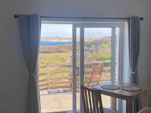 a room with a table and a balcony with a view at Dondie's House, Kilchoan in Kilchoan
