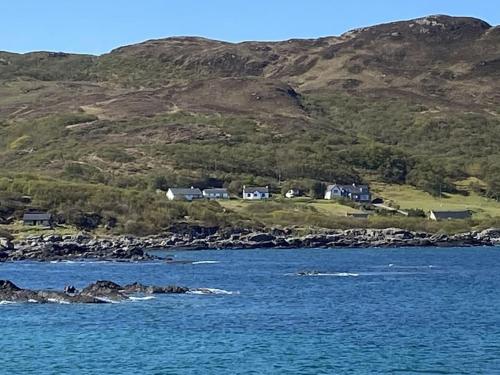 un grupo de casas en una colina junto al agua en Dondie's House, Kilchoan en Kilchoan