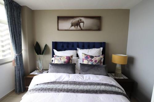 a bedroom with a bed with a blue headboard and pillows at Shangri-la Doonside in Kingsburgh