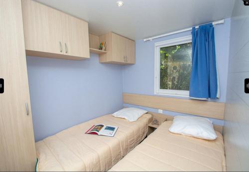 Duas camas num pequeno quarto com uma janela em Camping St Jean - Moustiers Ste Marie em Moustiers-Sainte-Marie