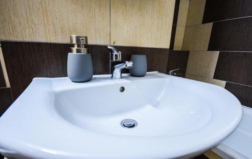 a white sink with two cups on top of it at Flower Apartment - Deluxe in Odorheiu Secuiesc