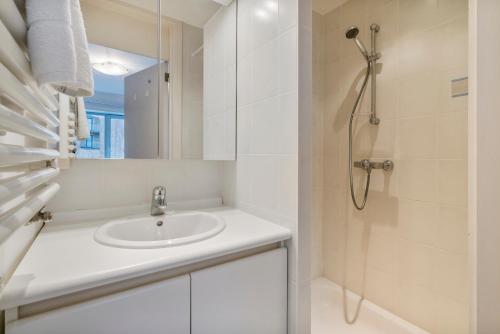 een badkamer met een wastafel en een douche bij Lichtrijk appartement in hartje Knokke vlak bij shoppingstraat & strand in Knokke-Heist