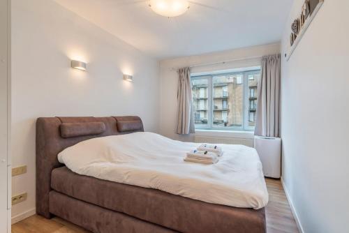 een slaapkamer met een groot bed en een raam bij Lichtrijk appartement in hartje Knokke vlak bij shoppingstraat & strand in Knokke-Heist