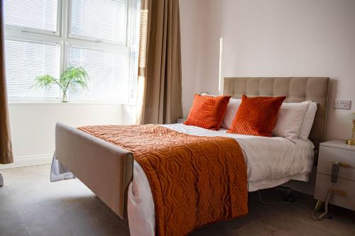 een slaapkamer met een bed met oranje kussens en een raam bij Liberty Redcar in Redcar