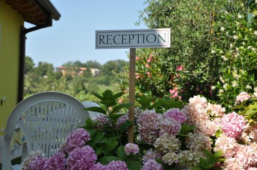 a sign in a garden with purple flowers at Agriturismo ai Ciliegi in Bardolino