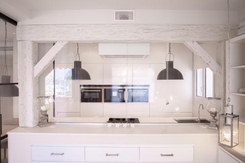 une cuisine avec des armoires blanches et des lampes suspendues noires dans l'établissement 