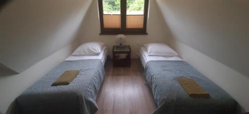 two beds in a small room with a window at Apartamenty Pod Caryńską in Ustrzyki Górne