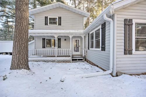 a white house with a tree in the snow at Spacious Home with Deck on Lake Chetek! in Chetek