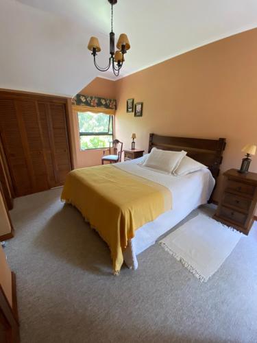 1 dormitorio con 1 cama grande con manta amarilla en Hermosa Casa en Bosques Puerto Pucón MÍNIMO 3 NOCHES DE ARRIENDO, en Pucón