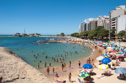 una multitud de personas en una playa con sombrillas en Apartamento Aconchegante Familiar - 3 Quartos - Guarapari - Centro, en Guarapari