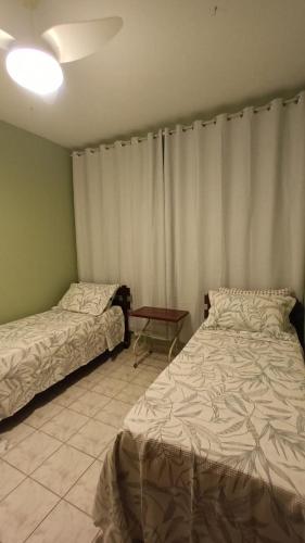 1 dormitorio con 2 camas y mesa. en Apartamento Aconchegante Familiar - 3 Quartos - Guarapari - Centro, en Guarapari