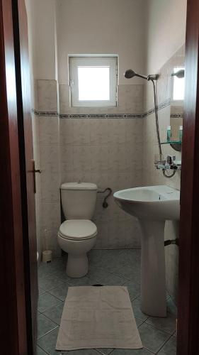 a bathroom with a toilet and a sink and a window at Guesthouse Villa Joanna&Mattheo in Sarandë