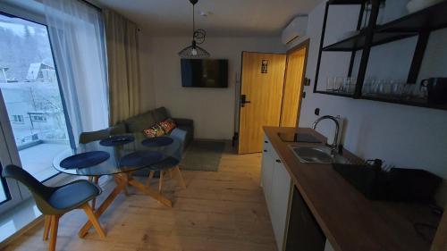 a kitchen and living room with a table and a couch at Apartamenty Nowa Osada - by VillaOlimpijska2 in Wisła