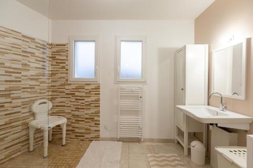 a white bathroom with a sink and a chair at La Janne - Maison avec jardin in Saujon