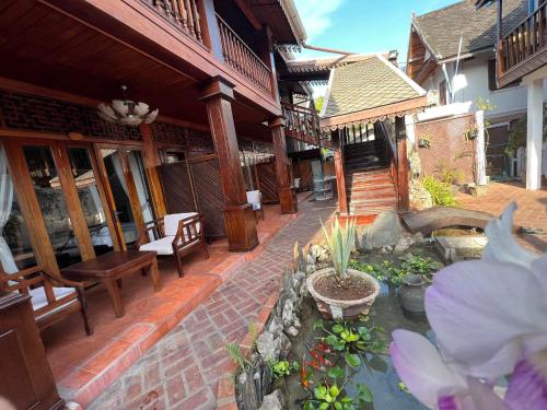 a patio of a house with a pond and flowers at Chaluenxay Boutique hotel in Luang Prabang