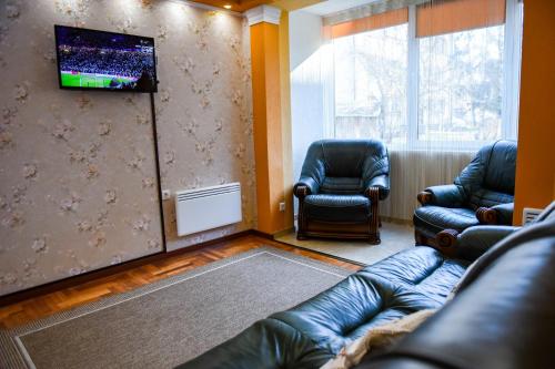 een woonkamer met 2 leren stoelen en een televisie bij Flower Apartment - Standard in Odorheiu Secuiesc
