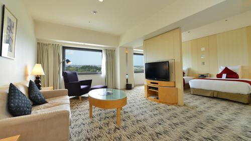 a hotel room with a couch and a bed and a television at ANA Crowne Plaza Narita by IHG in Narita