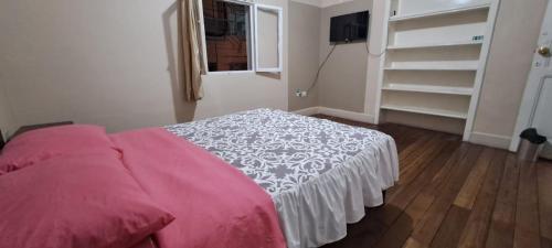 1 dormitorio con cama rosa y ventana en Magic Hostal, en Quito