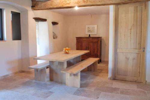 a table and benches in a room with a door at Gite le Roucayral , vue imprenable sur St Cirq Lapopie, deux chambres climatisées in Tour-de-Faure