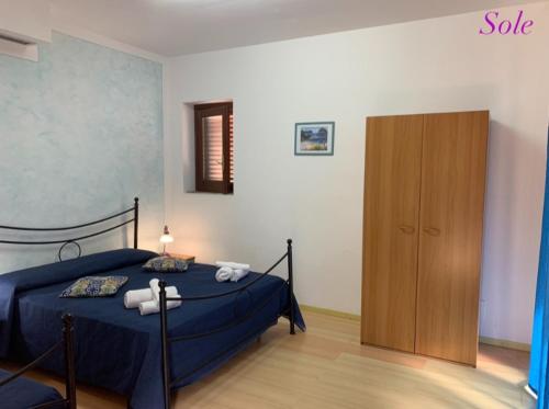 1 dormitorio con cama azul y armario de madera en Casa Sole e Luna, en Canneto