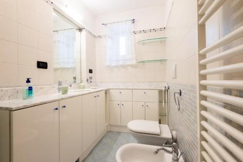 a white bathroom with a toilet and a sink at Waterfront House in Genova