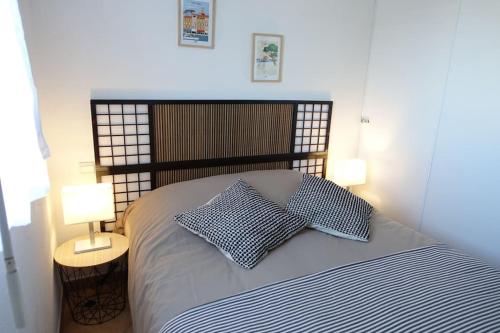 ein Schlafzimmer mit einem Bett mit zwei Kissen und zwei Lampen in der Unterkunft Port Marine - T3 calme, avec terrasse, piscine, près de la plage in Sainte-Maxime