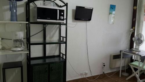 a room with a microwave and a tv on a shelf at Mer - Plage Lazaret in Sète