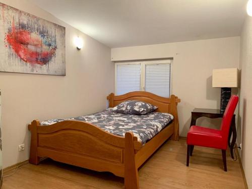 ein Schlafzimmer mit einem Bett und einem roten Stuhl in der Unterkunft Apartament z tarasem w Augustowie in Augustów