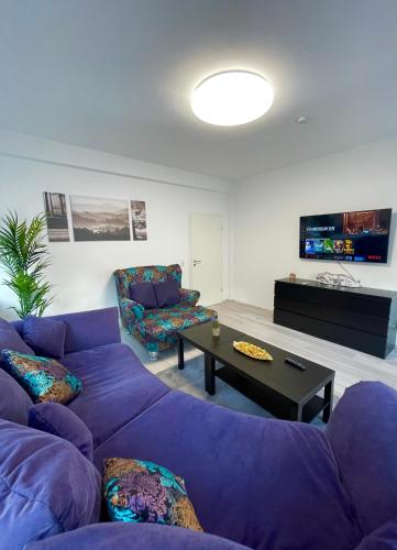 ein Wohnzimmer mit einem lila Sofa und einem Tisch in der Unterkunft Elite Rooms - Netflix - Coffee - WiFi - City in Wuppertal