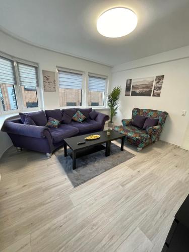 ein Wohnzimmer mit einem lila Sofa und einem Tisch in der Unterkunft Elite Rooms - Netflix - Coffee - WiFi - City in Wuppertal