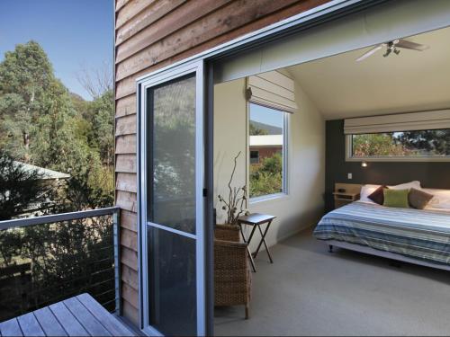 a bedroom with a bed and a balcony at At The Gap Holiday Home in Halls Gap