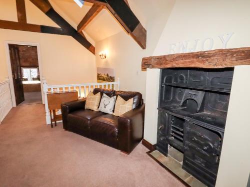 a living room with a leather chair and a fireplace at Meadow Place in Ipstones
