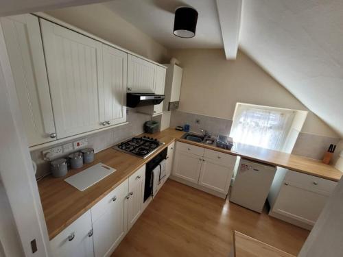 a kitchen with white cabinets and a stove top oven at Spacious cosy apartment in Llandudno