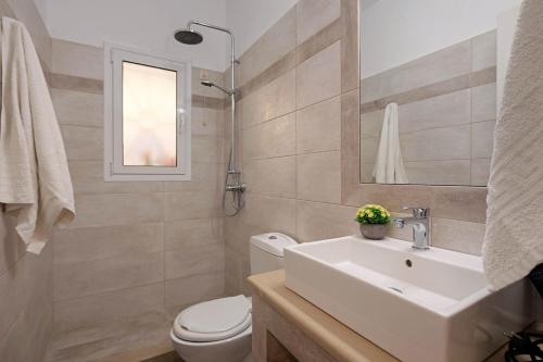 a bathroom with a sink and a toilet and a mirror at Nissaki Sea View 201 by Sealand Villas in Nisakion