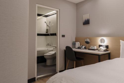 a hotel room with a bed and a desk and a toilet at Hubhotel Benqiao Inn Far Eastern Branch in Taipei