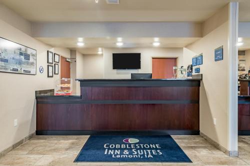 a lobby with a reception desk and a television at Cobblestone Inn & Suites - Lamoni in Lamoni