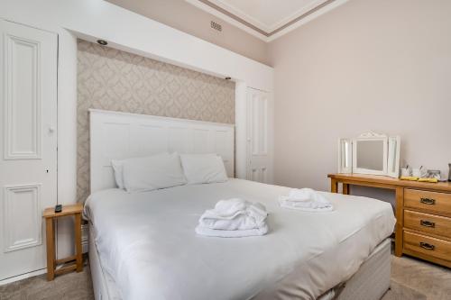 a bedroom with a white bed with two towels on it at Central Belfast Apartments Harpers in Belfast