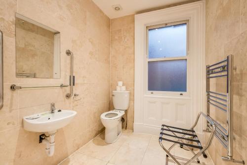a bathroom with a sink and a toilet and a window at Central Belfast Apartments Harpers in Belfast
