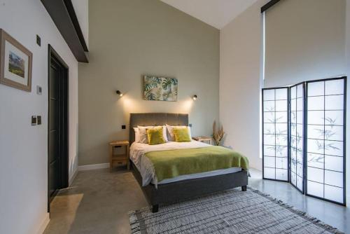 a bedroom with a bed with a green blanket at The Barn in Sandwich