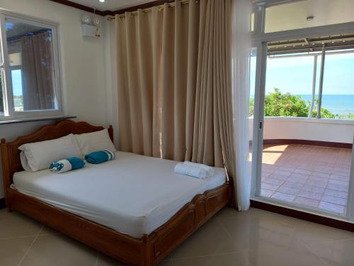 a bedroom with a bed with a window and a balcony at Seven Waves Beachfront Vacation Home, Bauang La Union 