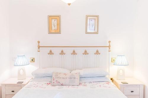 1 dormitorio con 1 cama blanca y 2 lámparas en Stables Cottage Far Sawrey Windermere, en Far Sawrey