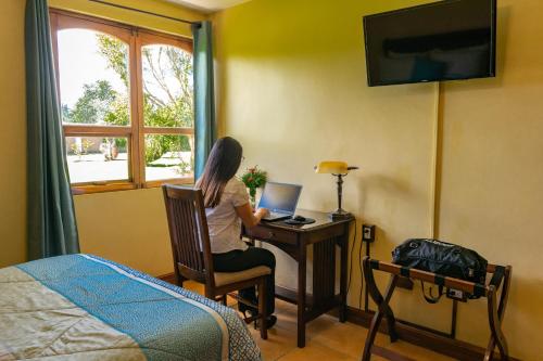 una mujer sentada en un escritorio con un portátil en Hacienda Grande Hotel, en Quetzaltenango